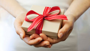 Woman holding small present with red bow wrapped around it